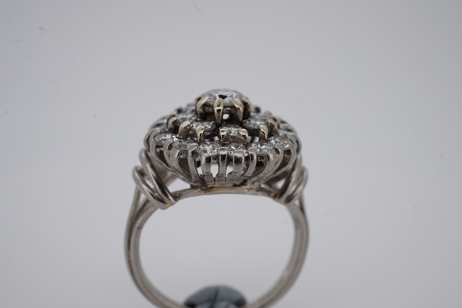 A white metal and diamond cluster set dress ring, with 'wire work' shoulders, size H, gross weight 5.2 grams. Condition - fair to good